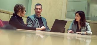 people sitting around a meeting table with a laptpop